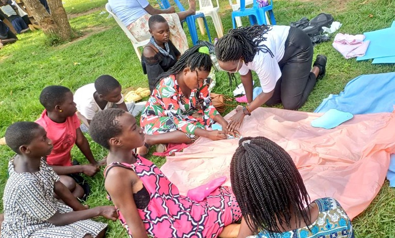 Jovia Kusiima (wearing white T-shirt) teaching young girls how to make reusable pads