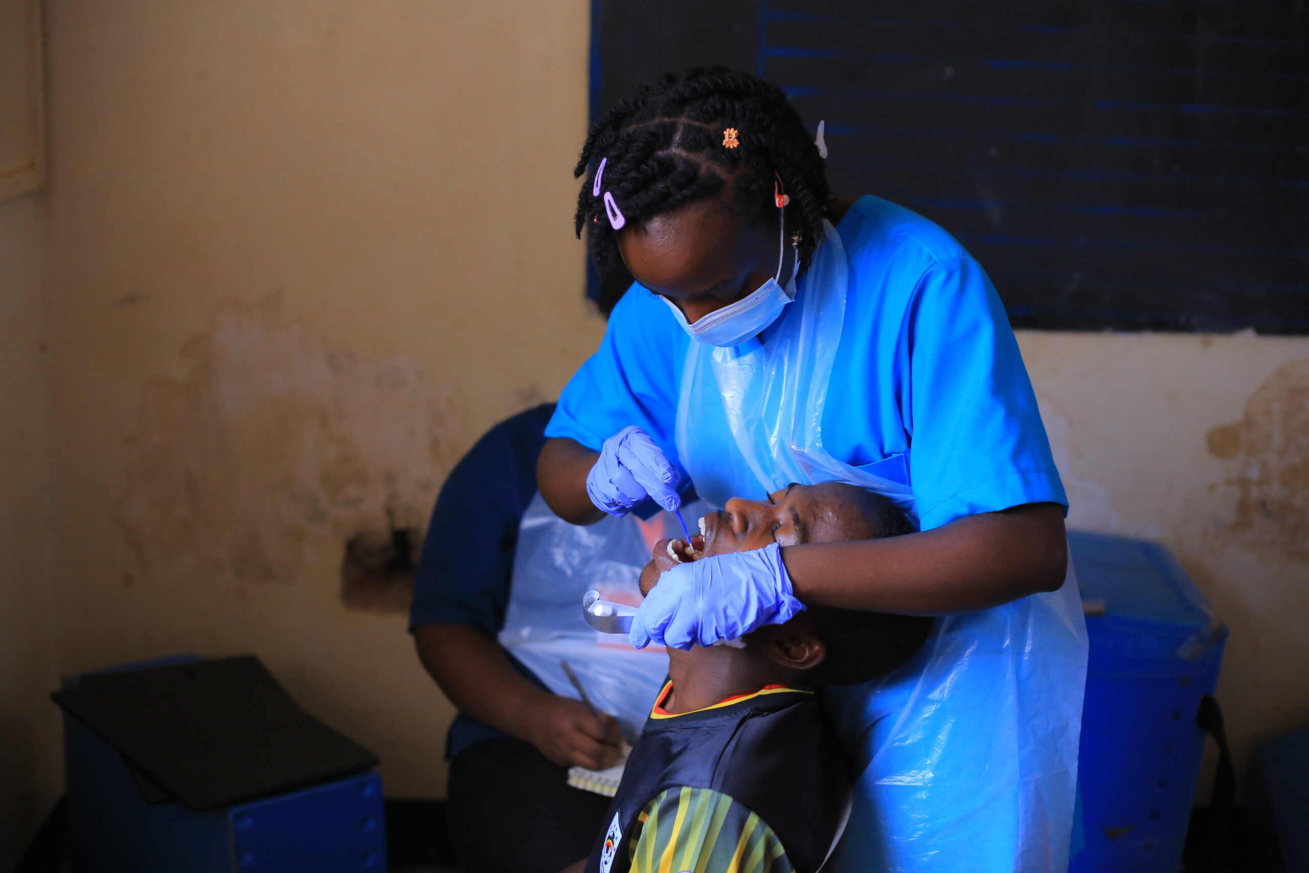 A student, Hannah Nakiwala Assumpta, performs a procedure on a patient at the medical camp.