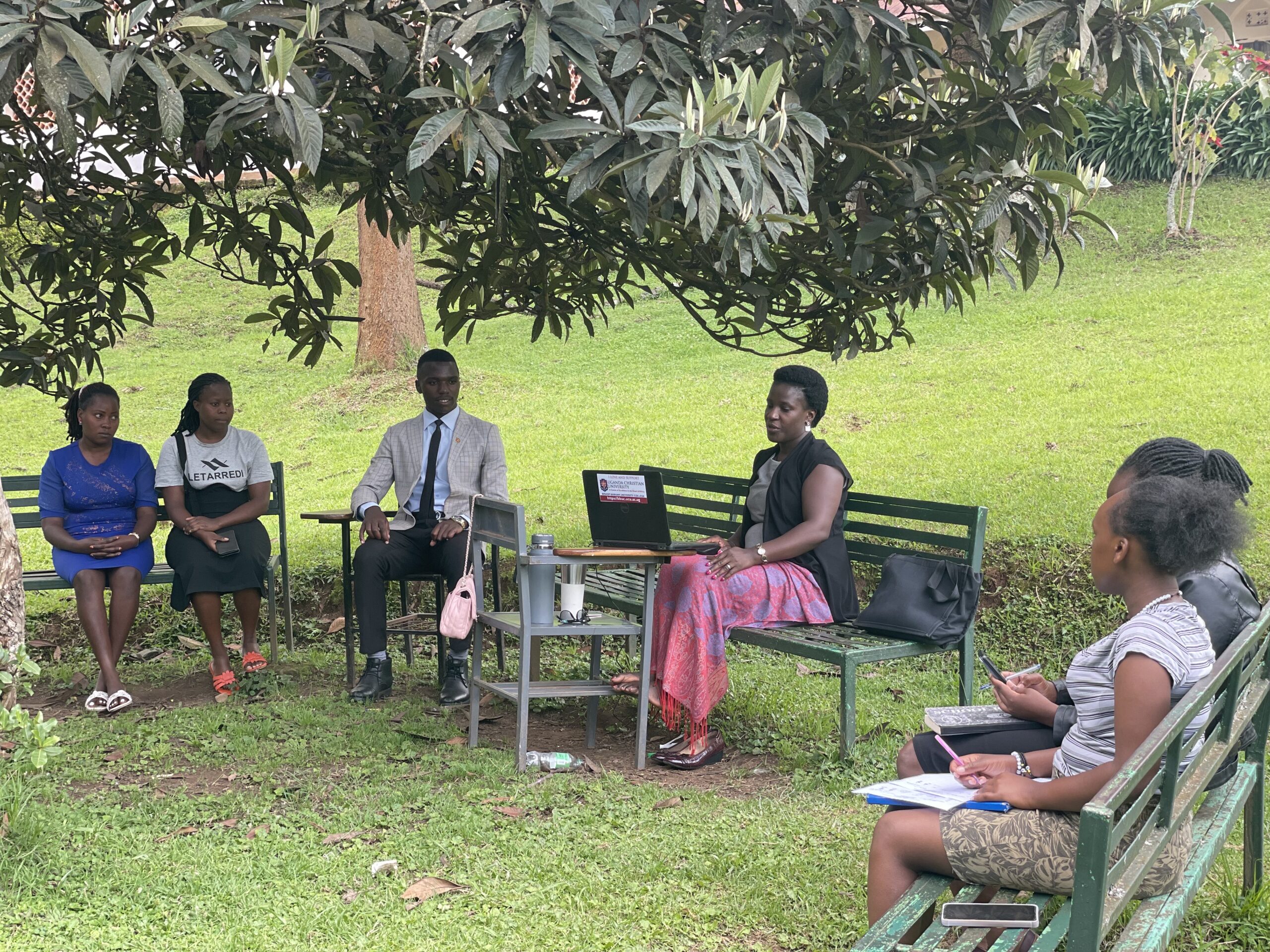 Patience Najuna, a lecturer at Bishop Barham University College, teaches a business law class outside under a tree.